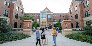 Students in conversing in front of residence halls Students in conversing in front of residence halls